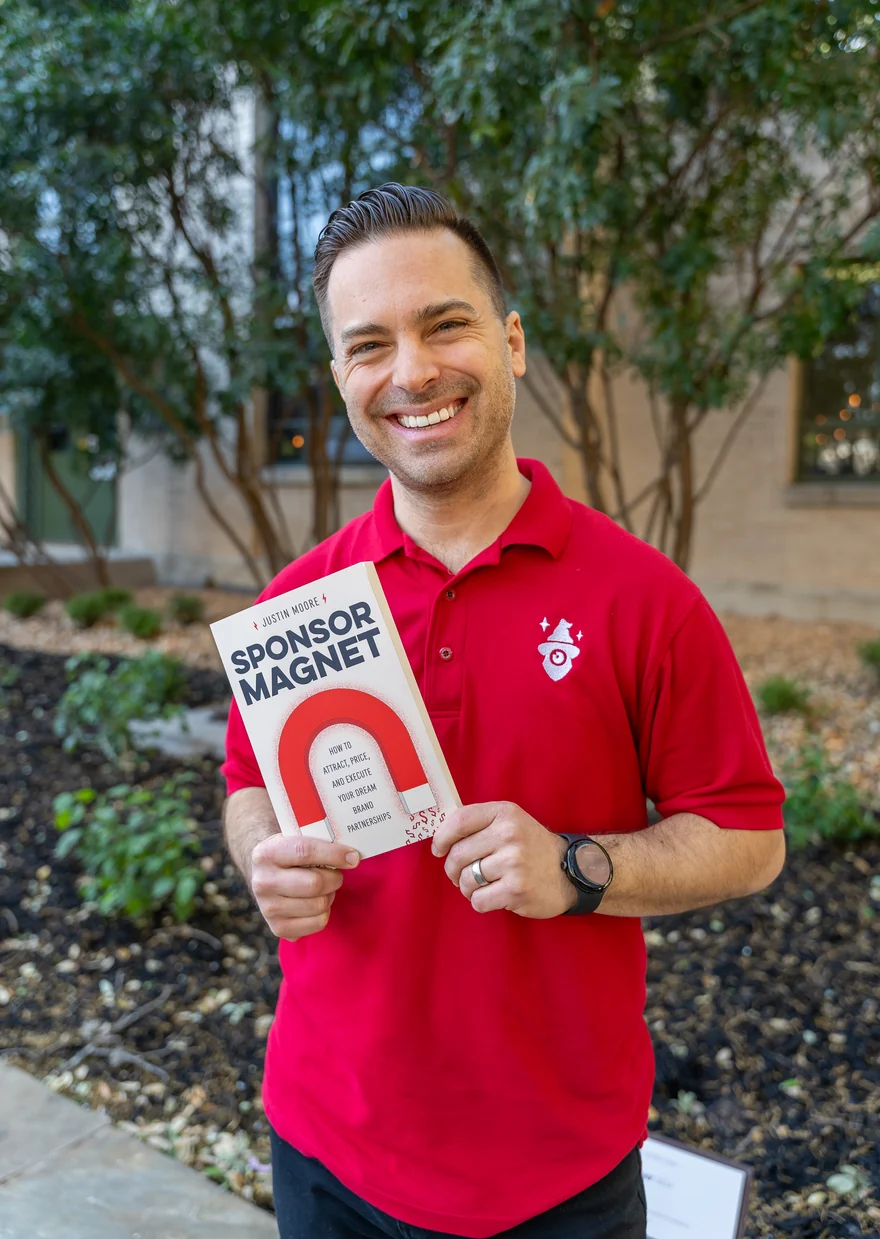 Justin Moore holding a copy of his book Sponsor Magnet.